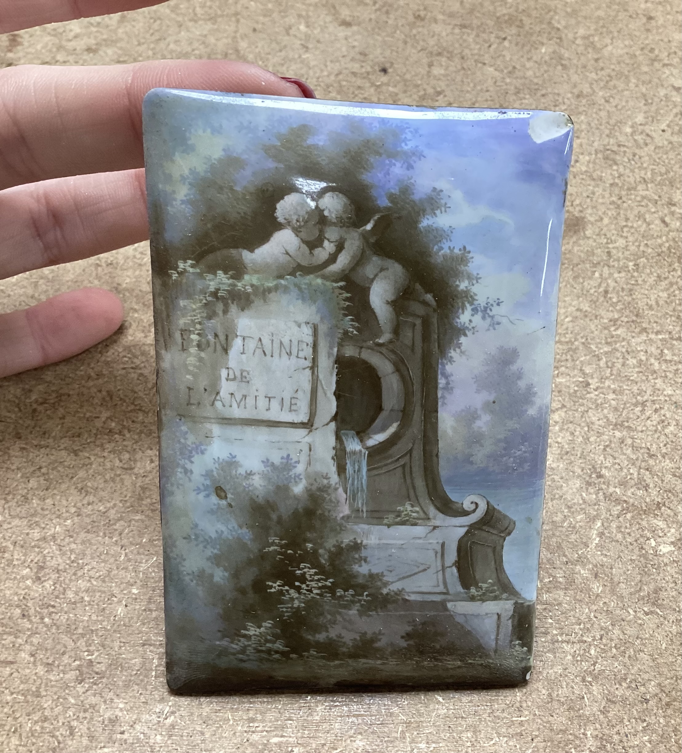A French Palais Royale easel enamel plaque, inscribed ’’Fontaine de L'amitie’’ [fountain of friendship], retailed by Rodrigues of Piccadilly, 16.5cm high